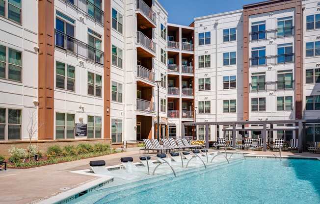 an outdoor swimming pool with chaise lounge chairs and a building in the background