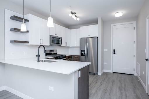 A kitchen with white cabinets and a stainless steel refrigerator.