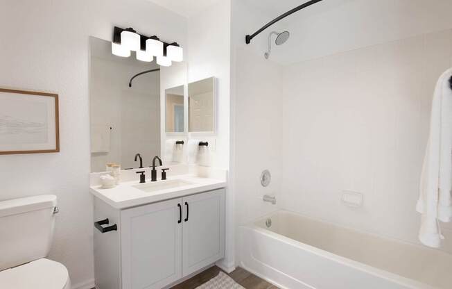 A white bathroom with a white tub, sink, and toilet.
