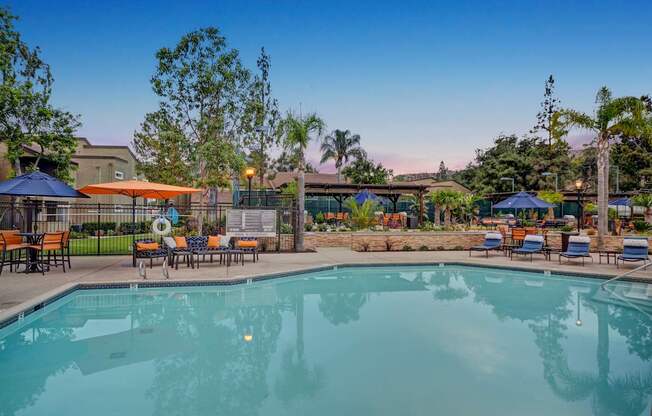A large swimming pool surrounded by lounge chairs and umbrellas.