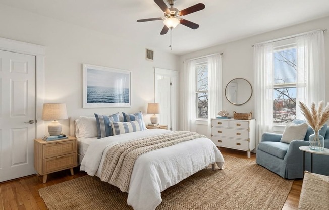 A bedroom with a large bed, a ceiling fan, and a view of the ocean through a window.