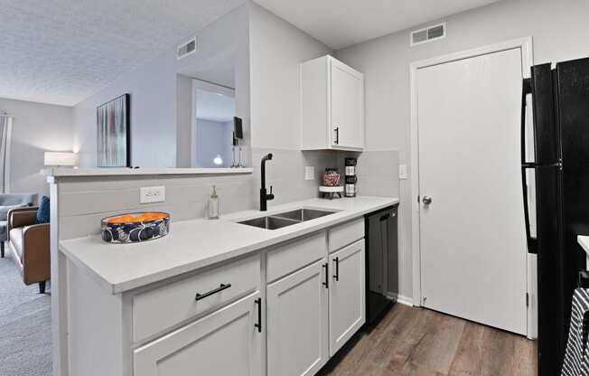 a kitchen with white cabinets and a sink and a refrigerator