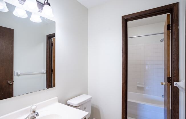 a bathroom with a mirror and a toilet and a shower.  Eagan, MN Glen Pond Apartments