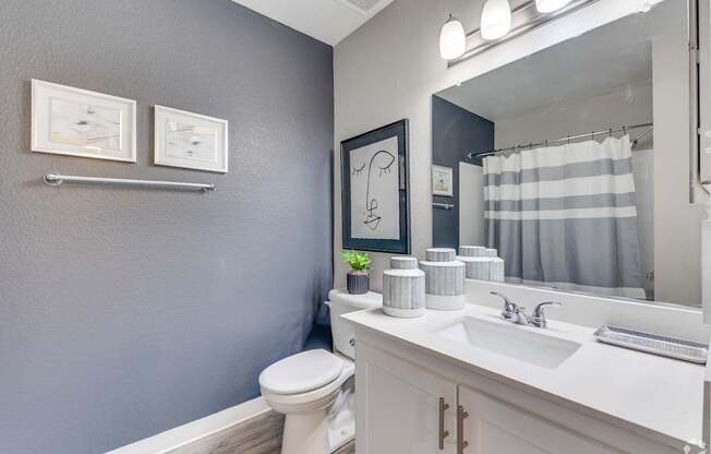 A bathroom with a toilet, sink, and mirror.