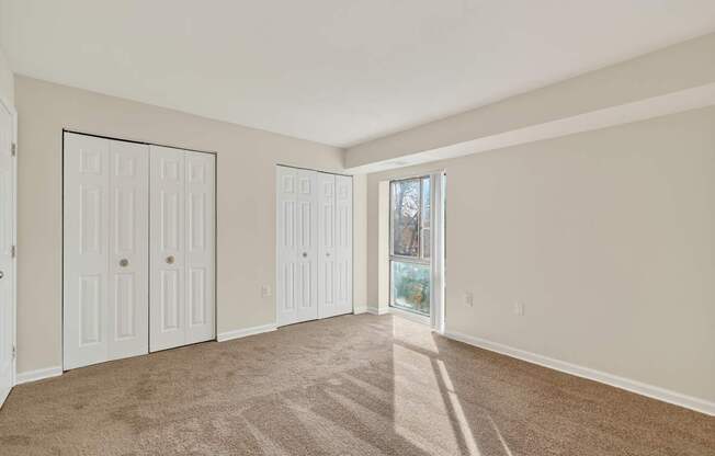 A room with white doors and carpeted floor.