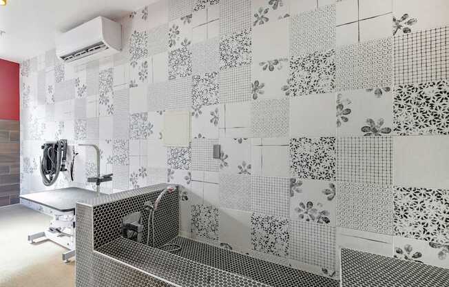 A bathroom with a tiled wall and a shower.