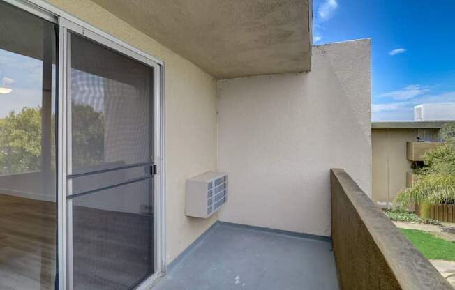 A balcony with a sliding glass door and a concrete wall.