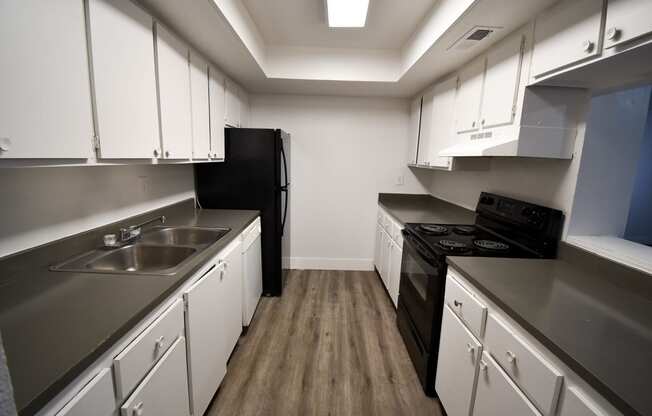 an empty kitchen with white cabinets and black appliances