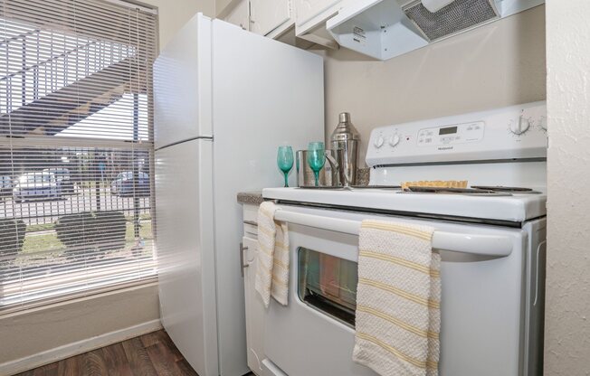 A white refrigerator and stovetop oven in a kitchen with a window at The Drake in Bossier City, LA