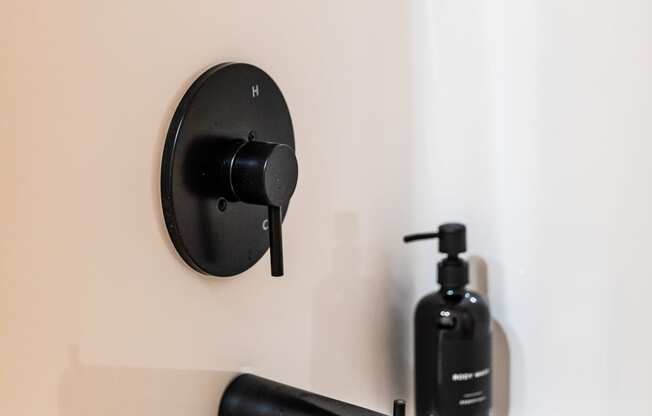 a bathroom with a black sink faucet and black soap dispenser