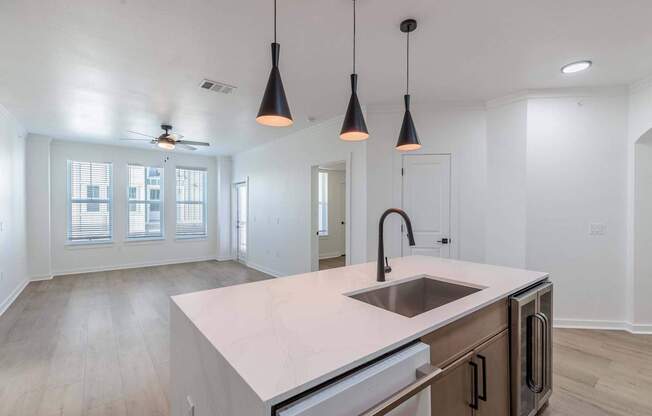 A kitchen with a sink, stove, and a ceiling fan.
