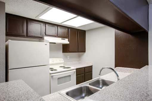 A kitchen with brown cabinets and a white fridge.