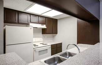 A kitchen with brown cabinets and a white fridge.
