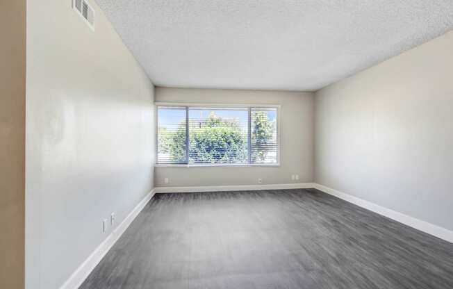 an empty living room with a window and wood floors