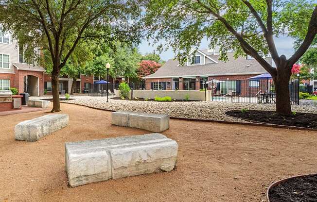 A playground with a red dirt surface and a few trees.