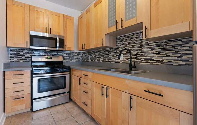 A kitchen with wooden cabinets and a stone backsplash at Brookmore Apartments Pasadena, CA