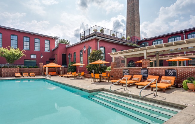 View of Pool Area, Showing Loungers, Cabanas, Picnic Areas, and Building Exterior and Mill at Alpha Mill Apartments