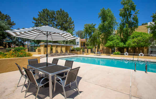 a swimming pool with a table and chairs under an umbrella