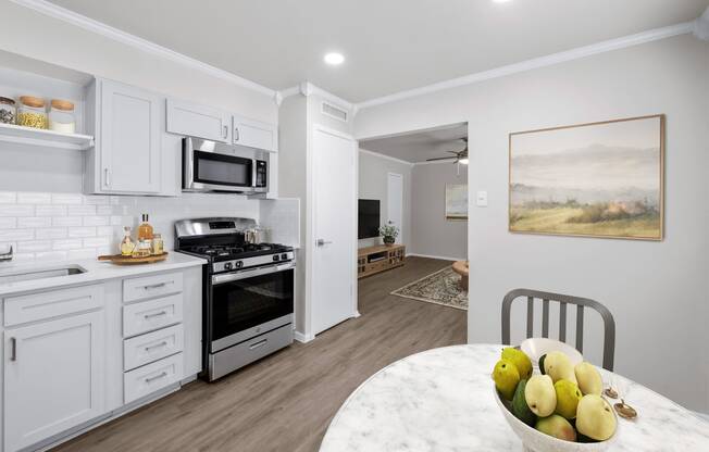 a kitchen with white cabinets and a white marble table with a bowl of fruit on it  at Sunset Heights, San Antonio, TX, 78209