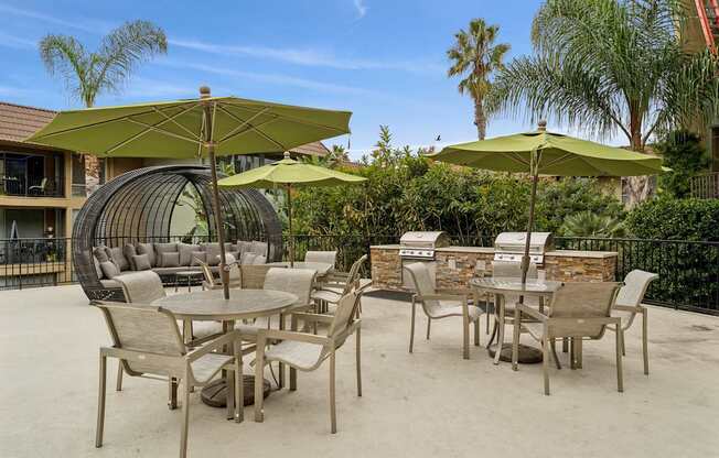 A patio with chairs and tables under umbrellas.