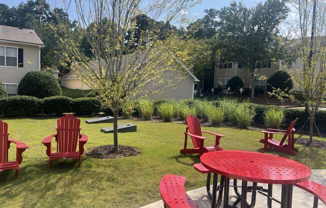 a patio with red chairs and a table in a yard