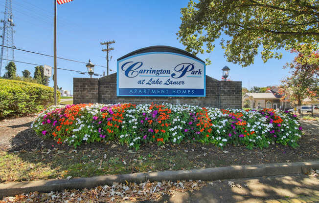 A sign for Carrington Park at Lake Lea Lure with a flower bed in front.