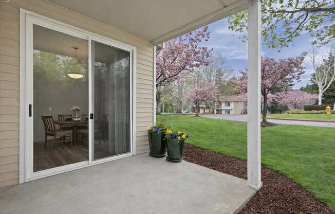 A patio with a table and chairs is covered by a glass door.