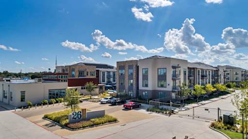 A modern building complex with a clear blue sky and some clouds above.