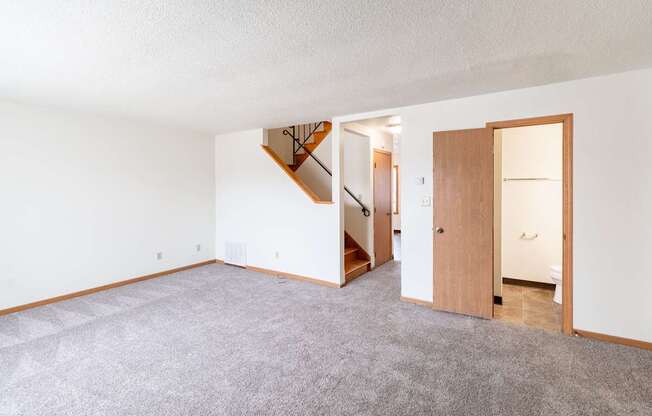A room with a carpeted floor and a staircase. West Fargo, ND Sheyenne Terrace Townhomes