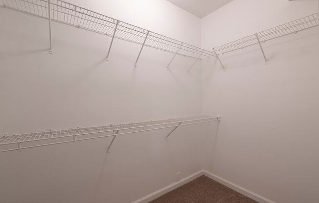 a walk in closet with white racks