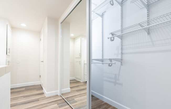 a walk in closet with a mirrored closet door in a white room