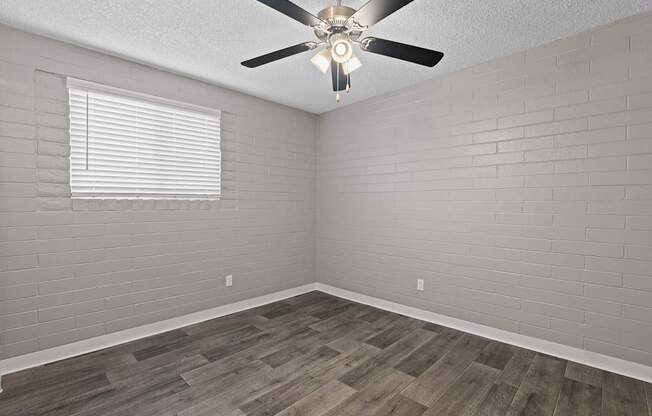 A room with a ceiling fan and wooden flooring.