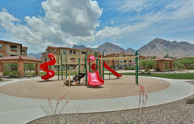 a playground with slides and other playground equipment in front of buildings