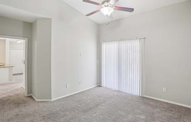 A room with a ceiling fan and carpeted floor.