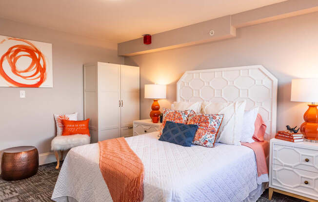 a bedroom with a white bed and orange pillows