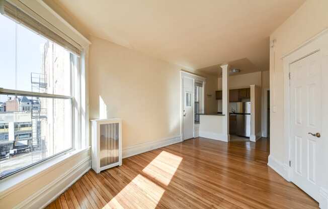 vacant living area with hardwood flooring, large windows and view of kitchen at dupont apartments in washington dc