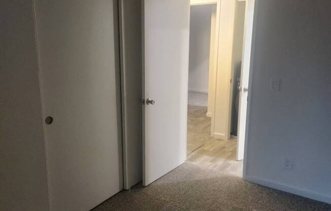 A hallway with a carpeted floor and two open doors.