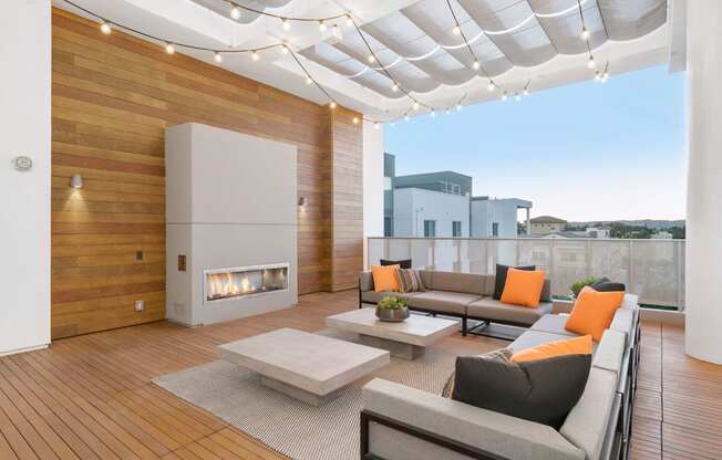 Two Bedroom Apartments in Woodland Hills, CA - The Q Variel - Outdoor Lounge with Couches, a Fireplace, Coffee Tables, String Lights, and City Views