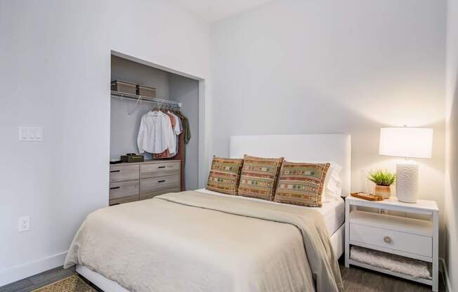 A bedroom with a bed, nightstand, and closet.