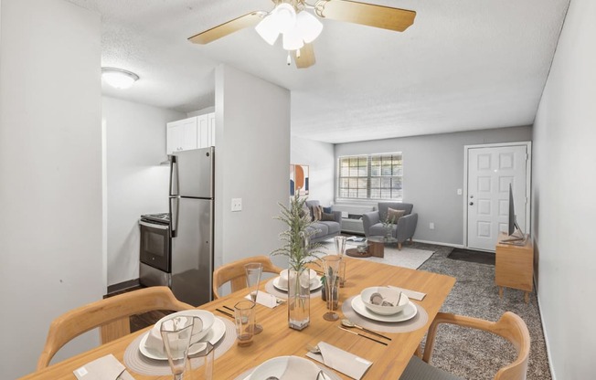 a dining area with a wooden table and chairs and a living room in the background