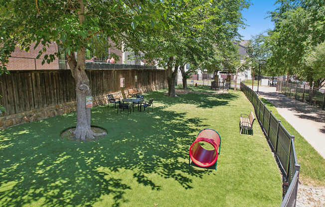 A backyard with a red slide and a green lawn.