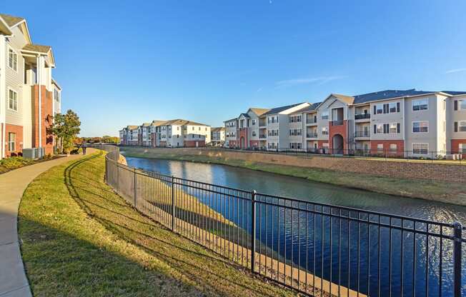 a river with a row of houses on the other side of it at Cumberland Place Apartment Homes, Texas