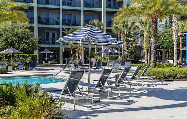 a group of lounge chairs and an umbrella next to a swimming pool