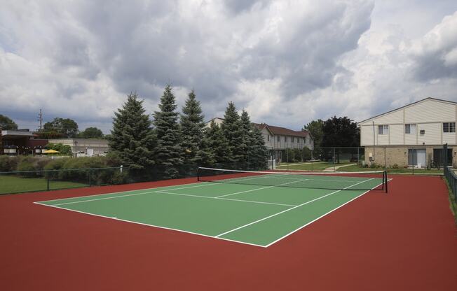 a tennis court with a house and trees in the background at Village Club of Rochester Hills, Michigan