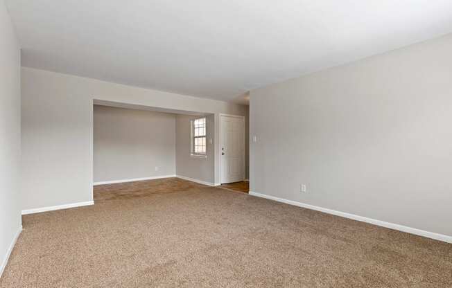 an empty living room with carpet and a door to a bedroom