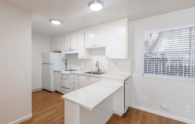 a white kitchen with white cabinets and a window