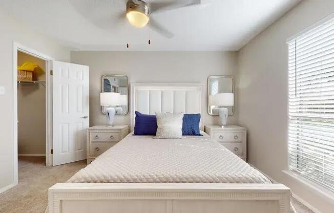 A bedroom with a large bed, two nightstands, and a ceiling fan.