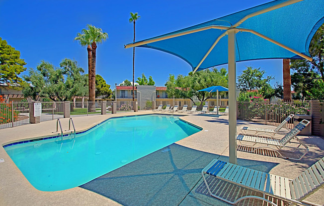 our resort style swimming pool is surrounded by chairs and umbrellas