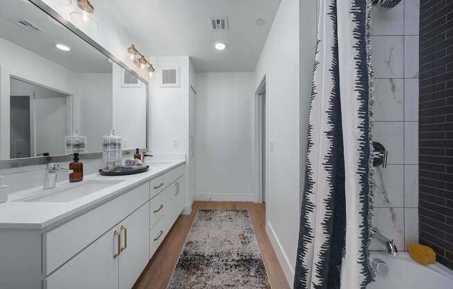 A bathroom with a white counter and a black and white shower curtain.