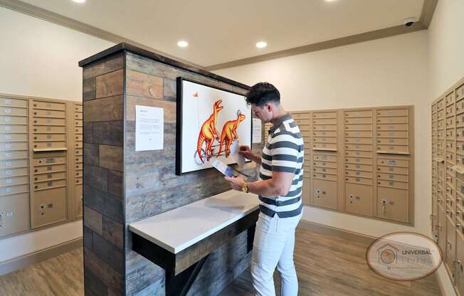 A man standing in front of the table in the mail room, looking through mail.